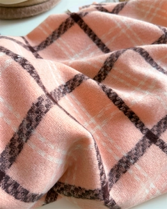 Close-up of soft pink plaid cashmere-like scarf showing warm wool texture and woven pattern