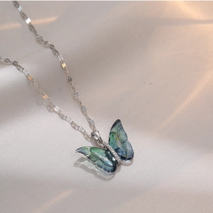 Elegant titanium steel butterfly necklace with gradient blue resin wings on silk background