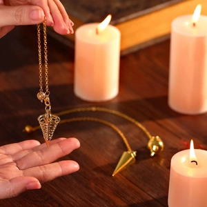 Detailed view of spiral and tapered gold metal pendulums for divination on wooden desk
