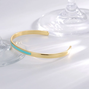 Minimalist gold-plated C-shaped open bracelet with blue enamel inlay on white background