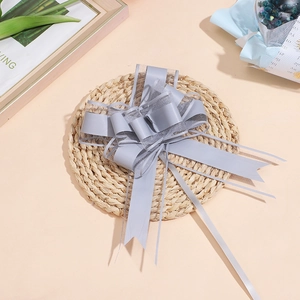 Grande fiocco in organza grigia per confezioni regalo eleganti su un tappeto di paglia