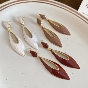 Close-up of hollow water drop earrings in cream, coffee, and wine red enamel finish