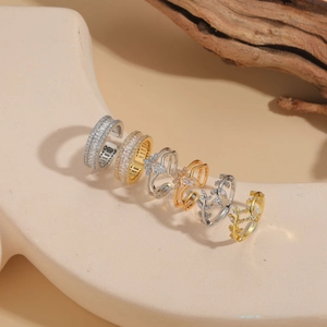 Dettaglio di eleganti anelli con zirconi a ramo in finiture argento, oro e oro rosa