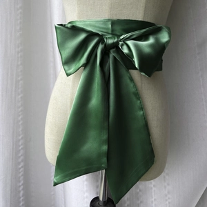 Vue détaillée d'une ceinture en satin vert foncé avec un grand nœud papillon élégant