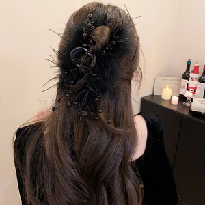Detail of black feather hair claw with elegant bead tassels on wavy hair