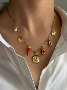 Detail of 18K gold bohemian necklace featuring heart, chili and pearl charms on model