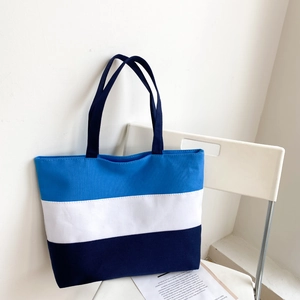 Three-color patchwork canvas tote bag with blue and white stripes on a white chair