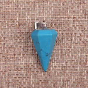 Macro detail of faceted turquoise gemstone cone pendant on a rustic linen background