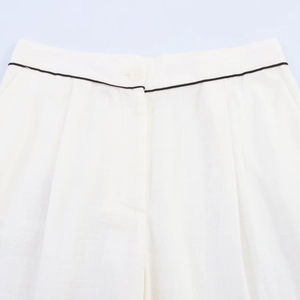 Detail of ivory white cotton linen waist with black piping and single button closure