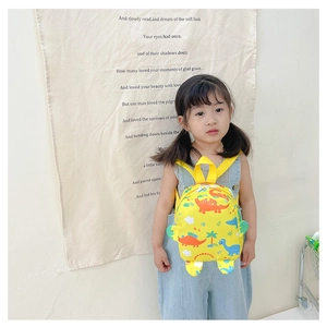 Detail showing cartoon dinosaur patterns and spine fins on yellow canvas kids backpack