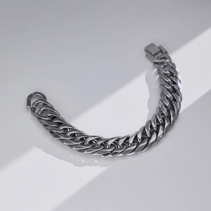 Dettaglio di un bracciale a catena cubana in acciaio con chiusura a scatto quadra