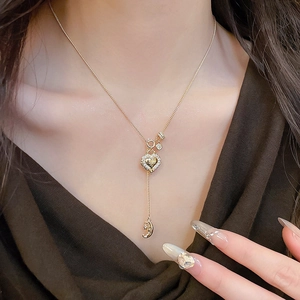 Detail of gold lucky bag heart necklace with zircons and moon pendant on collarbone