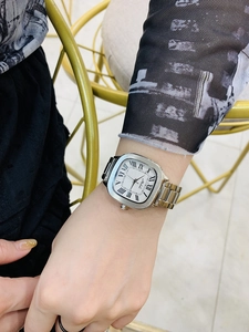 Elegant woman wearing square silver watch with Roman numerals and white dial display
