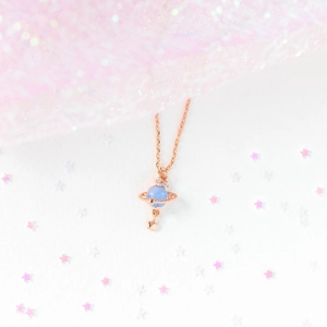 Detail of rose gold Saturn necklace featuring light blue bead and crystal planet ring