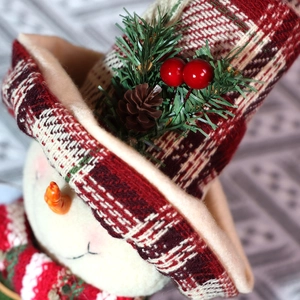Close-up of a Christmas snowman curtain buckle with red plaid hat and pine cone detail