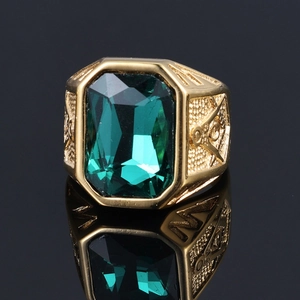 Macro detail of gold Freemason ring featuring a large rectangular emerald green gemstone