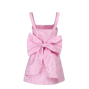 Détail du dos d'une robe rose pour fille avec grand nœud et tissu jacquard texturé