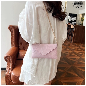 Rosa Glitzer-Umschlagtasche mit goldener Kette in einem modernen Café-Ambiente