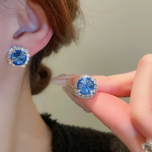 Detailansicht silberner quadratischer Ohrstecker mit blauem Edelstein und Kristallumrandung