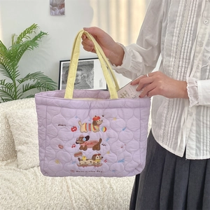 Close-up of purple quilted handbag with cute puppy embroidery and yellow handles
