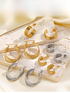 Collection of gold and silver C-shaped hoop earrings on marble and satin background