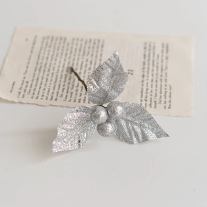 Silver glitter berry branch ornament for Christmas tree decoration on vintage book pages