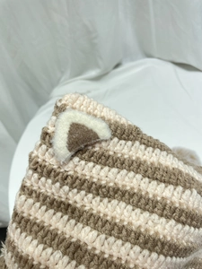 Detailed close-up of beige and brown striped crochet knit with fuzzy cat ear detail