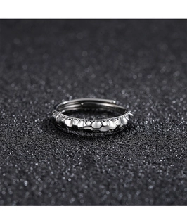 Macro shot of silver ring with irregular hammered texture on a black background