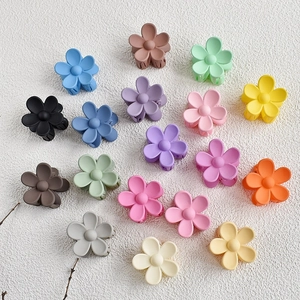 Flat lay of 18 matte flower hair clips in vibrant candy colors on white texture