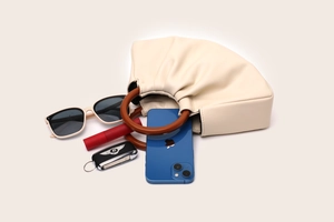 Detailed shot of pleated cream leather handbag with brown handles and lifestyle essentials