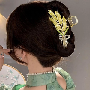 Macro view of golden wheat hair claw clip with rhinestones and green leaf details