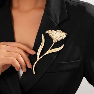 Artistic gold flower brooch with brushed metal texture on a black blazer jacket