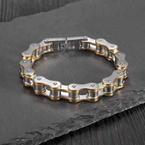 Macro shot of silver and gold bicycle chain bracelet on a dark textured slate background