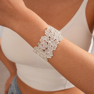 Detail showing wide silver open cuff bracelet with hollow floral lace pattern on wrist