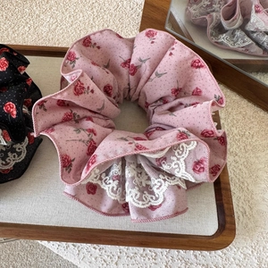 Détail d'un chouchou rose à fleurs avec dentelle sur un plateau aux reflets doux