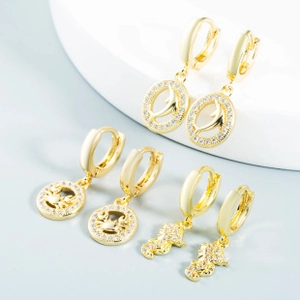 Close-up of golden sea creature earrings with dolphins, crabs, and seahorses on white stand