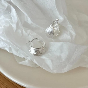 Macro detail of brushed S925 sterling silver hoop earrings showing the metal hallmark