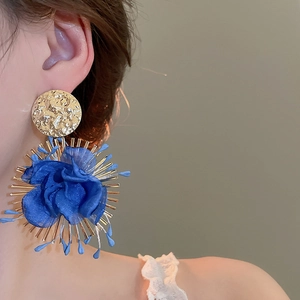 Detailed view of oversized blue chiffon flower earring with gold metallic texture and beads