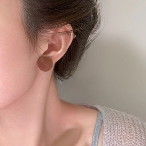 Detailansicht der braunen runden Samtohrstecker am Ohr für den Winter-Look