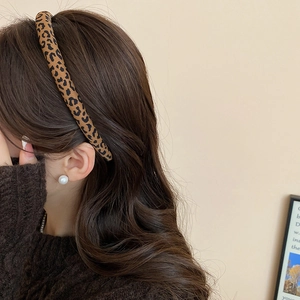 Serre-tête léopard tendance porté sur de longs cheveux bruns pour un look élégant
