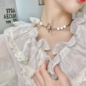 Detailed view of butterfly pearl necklace with heart pendant on model neckline