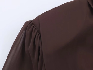 Dettaglio dell'abito marrone scuro con maniche a sbuffo e trama in chiffon plissettato