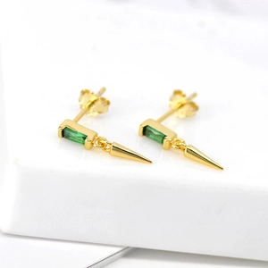 Close-up of S925 gold earrings with emerald green zircon and punk style cone spikes
