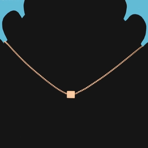 Close-up of a rose gold square pendant necklace on a minimalist silhouette display