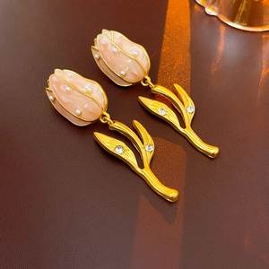 Macro shot of elegant tulip earrings with pink pearls and gold leaf diamond details