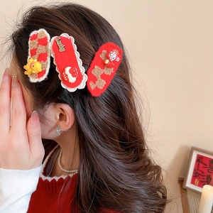 Gros plan sur trois pinces à cheveux rouges festives aux textures douces et breloques