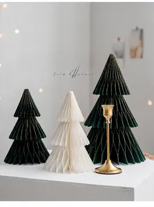 Three honeycomb paper Christmas trees and a golden candle holder in a Nordic setting