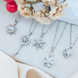 Five assorted silver pendant necklaces featuring sun, key, and snowflake designs