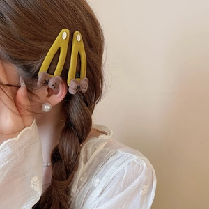 Detail showing two yellow velvet bear hair clips worn on a braided hairstyle