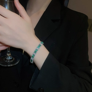 Detailed view of luxury silver bracelet with round green zircons worn on wrist